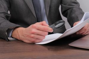 Close up of businessman using loupe for reading contract. Magnifying Glass and document. Lawyer minutely checking documents