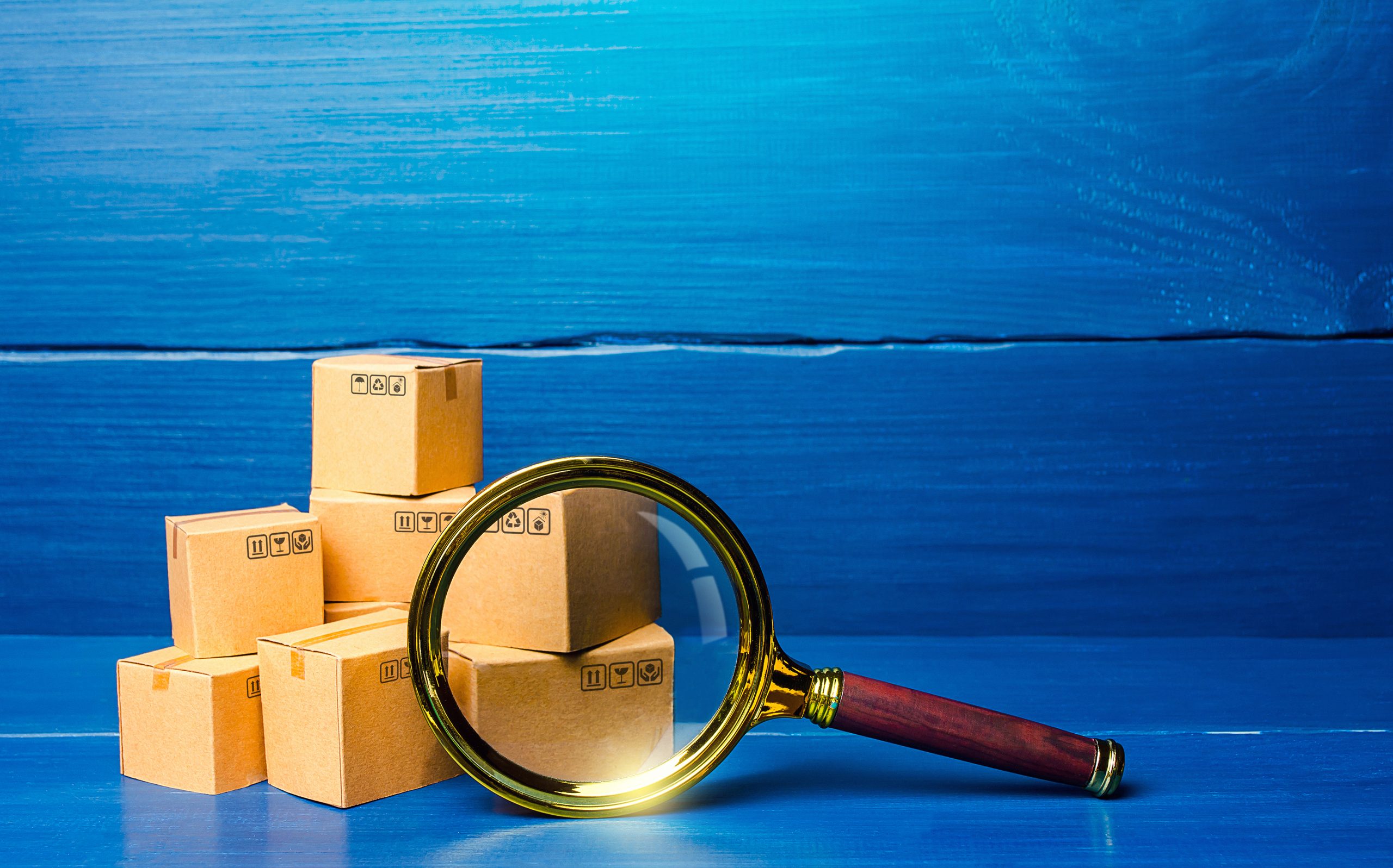 Cardboard boxes and magnifying glass. Concept of searching for goods and components. Procurement audit. Quality control. Supply and demand, distribution of products on the market. Cargo tracking